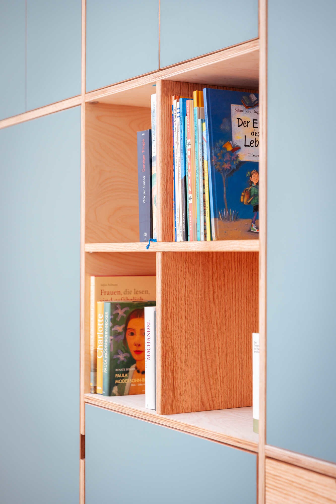 Maßgefertigter einbauschrank mit blauen türen und offenen regalfächern als bücherschrank nach maß unter der treppe.