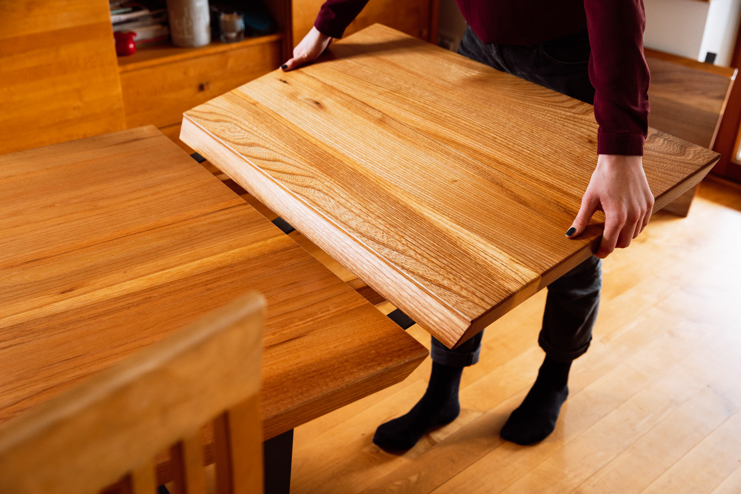 Detailaufnahme eines Massivholztisches: Die Tischverlängerung ist hochwertig verarbeitet und die schöne Maserung des Holzes erzeugt eine warme und gemütliche Atmosphäre. Das Design ist minimalistisch und elegant.