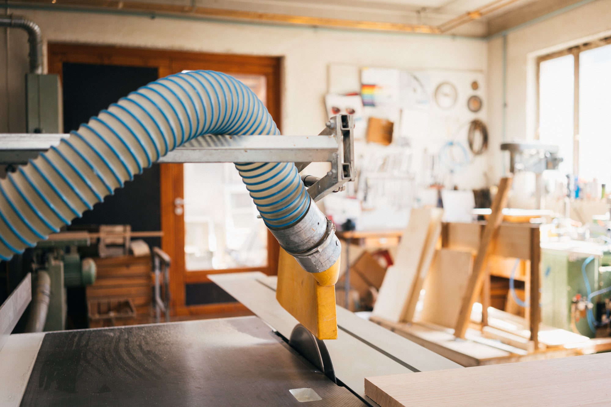 Helle Schreinerei-Werkstatt mit einer Formatkreissäge und anderen Holzbearbeitungsmaschinen. Das Bild zeigt hochwertiges Holz und eine moderne Arbeitsumgebung.