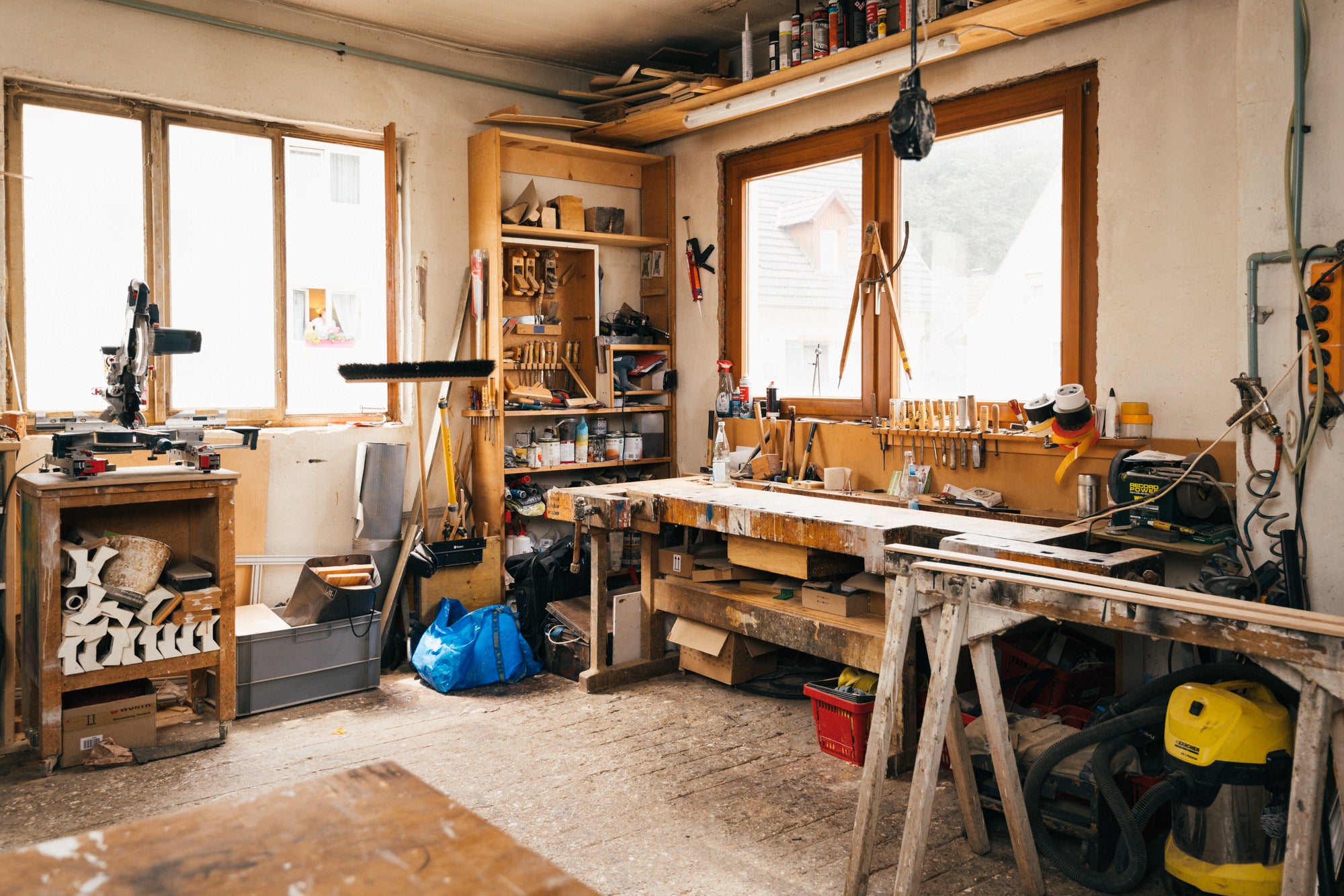 Gemütliche und sympathische Werkstatt, die durch viele Fenster hell erleuchtet ist. Auf der Werkbank liegen verschiedene Handmaschinen bereit.