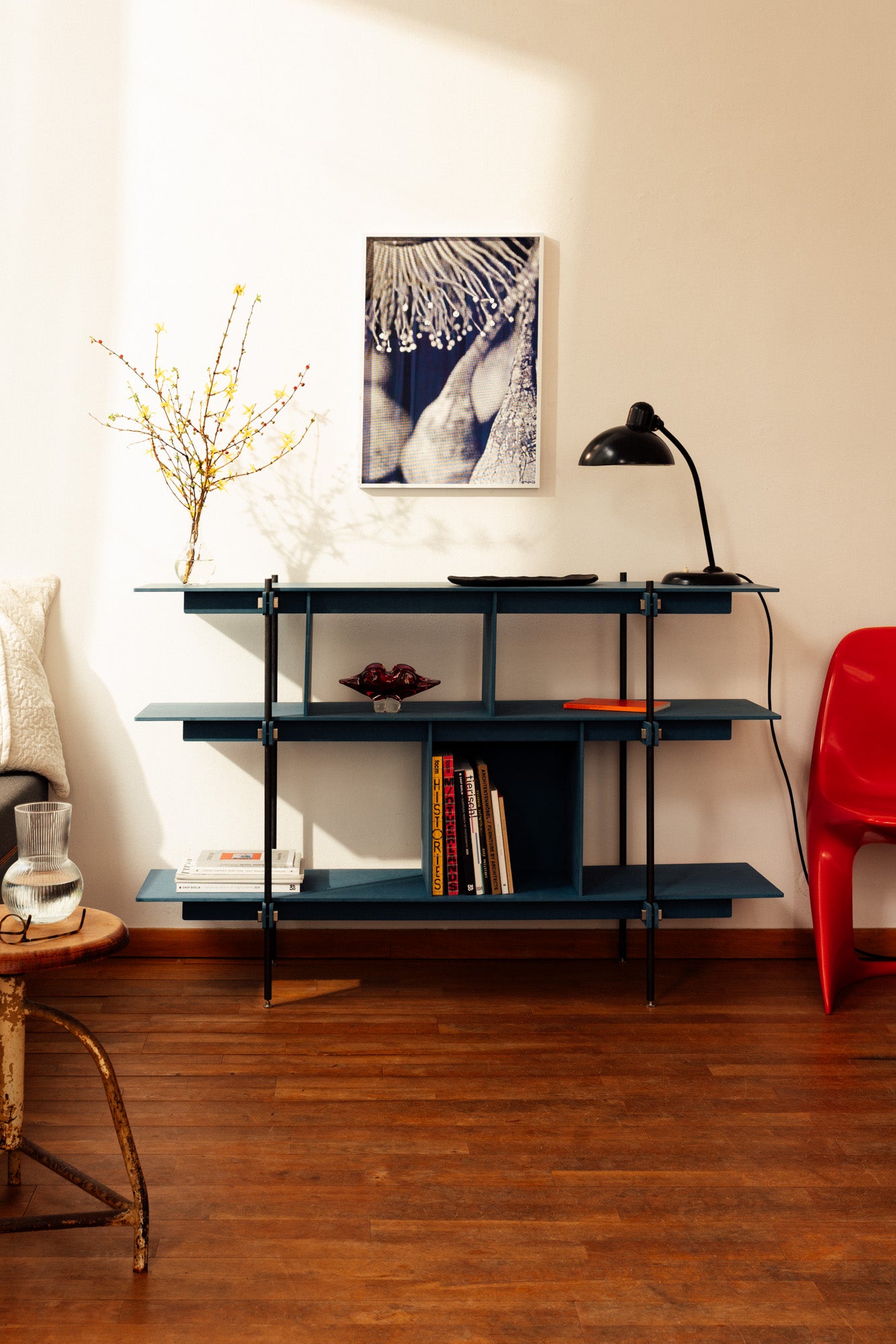 Modernes Holz und Stahl Regalsystem mit minimalistischem Design. Das Regal hat ein schlankes, schwarzes Stahlgestell und dunkelblaue Holzregalböden.