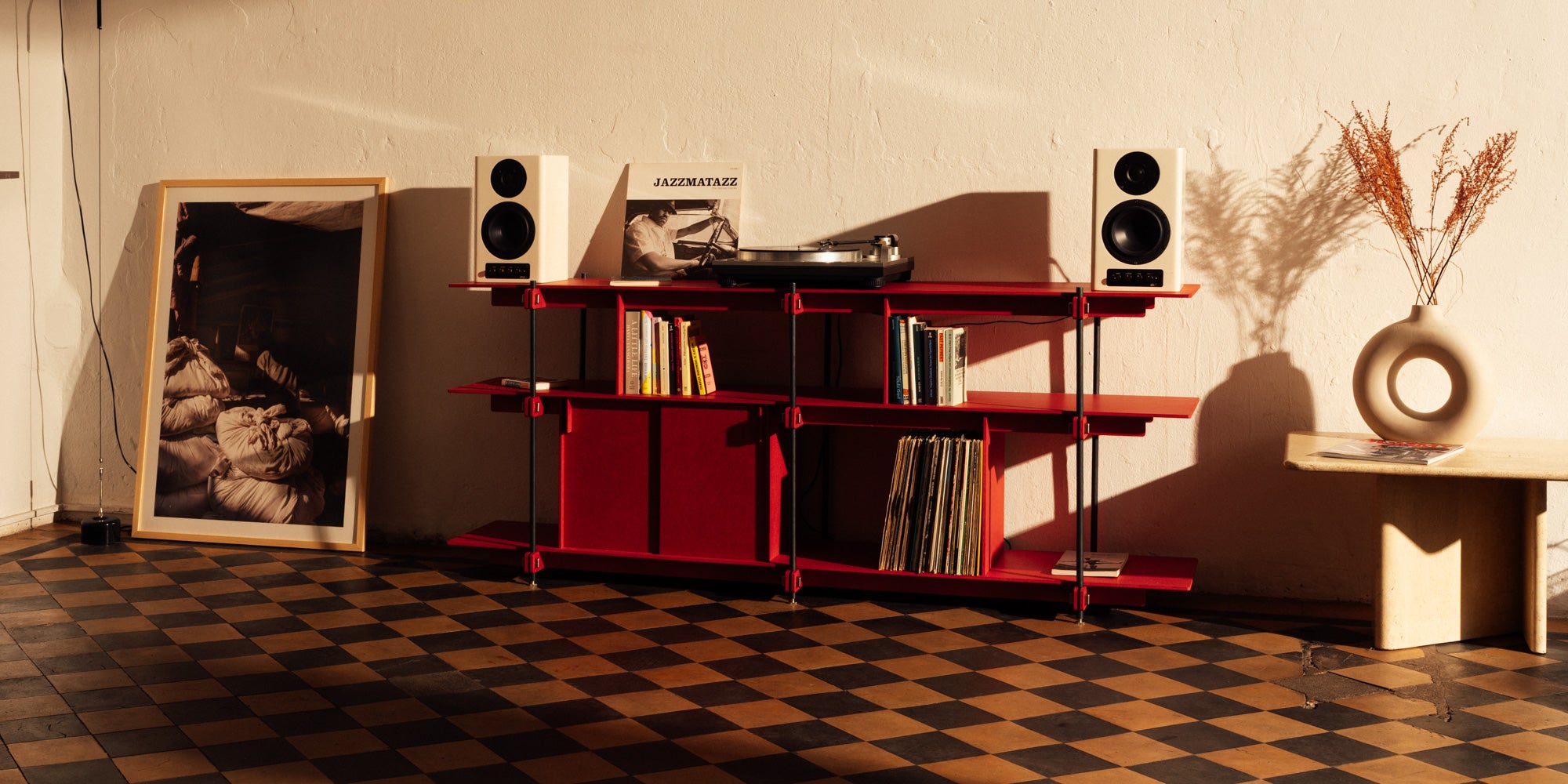 Modernes rotes Regal mit offener und geschlossener Aufbewahrung. Das Stahlregal steht auf einem auffälligen Schachbrett-Boden, der das Design hervorhebt.