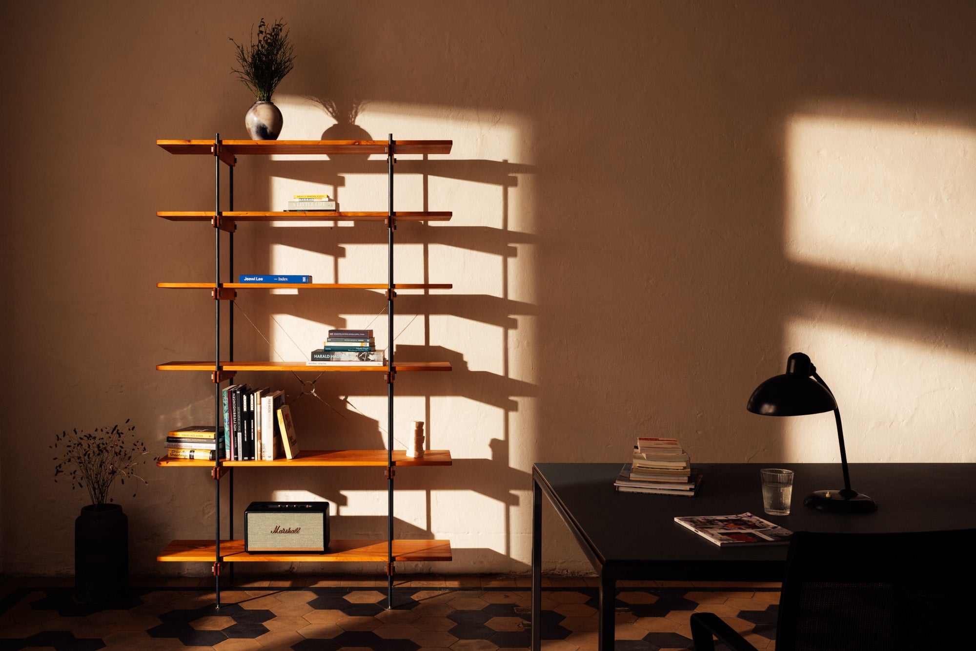 Ein minimalistisches Design-Regal aus massivem Kirschholz in einem sehr warmen, gemütlichen Licht. Die schöne Beleuchtung betont die Maserung des Holzes und den interessanten Fliesenboden.