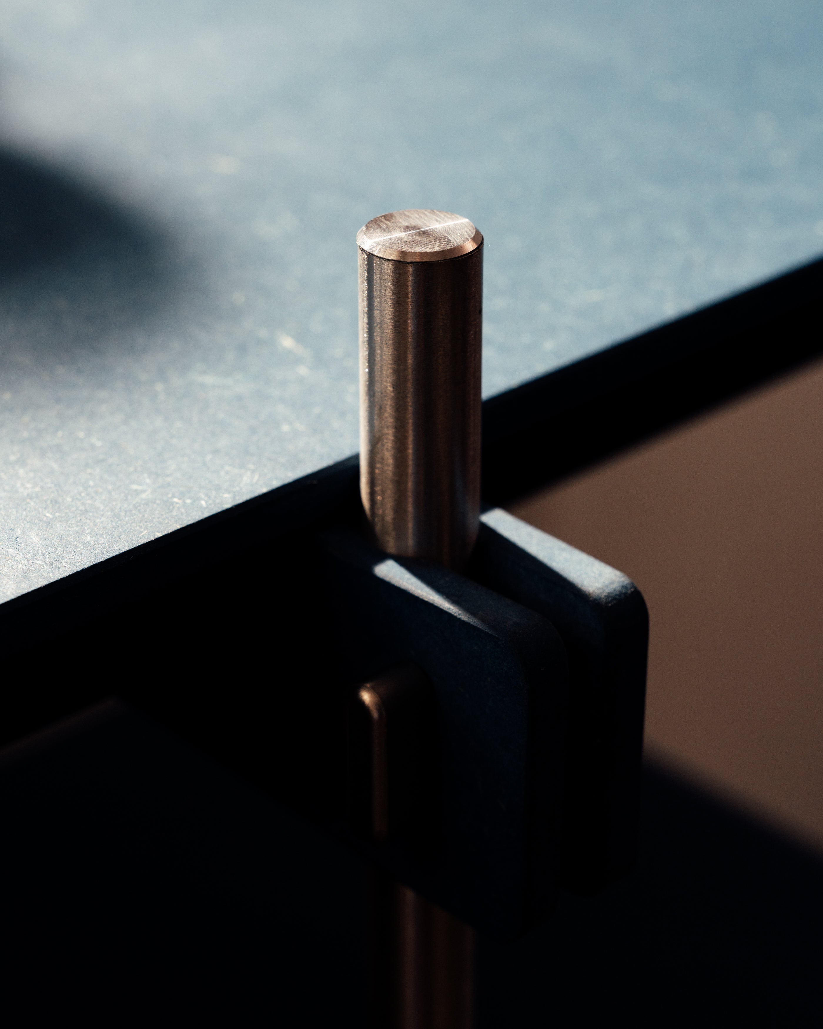 Dunkles Metall-Regalsystem mit vertikalem Rundstab und horizontaler Befestigung am Holztischkante.