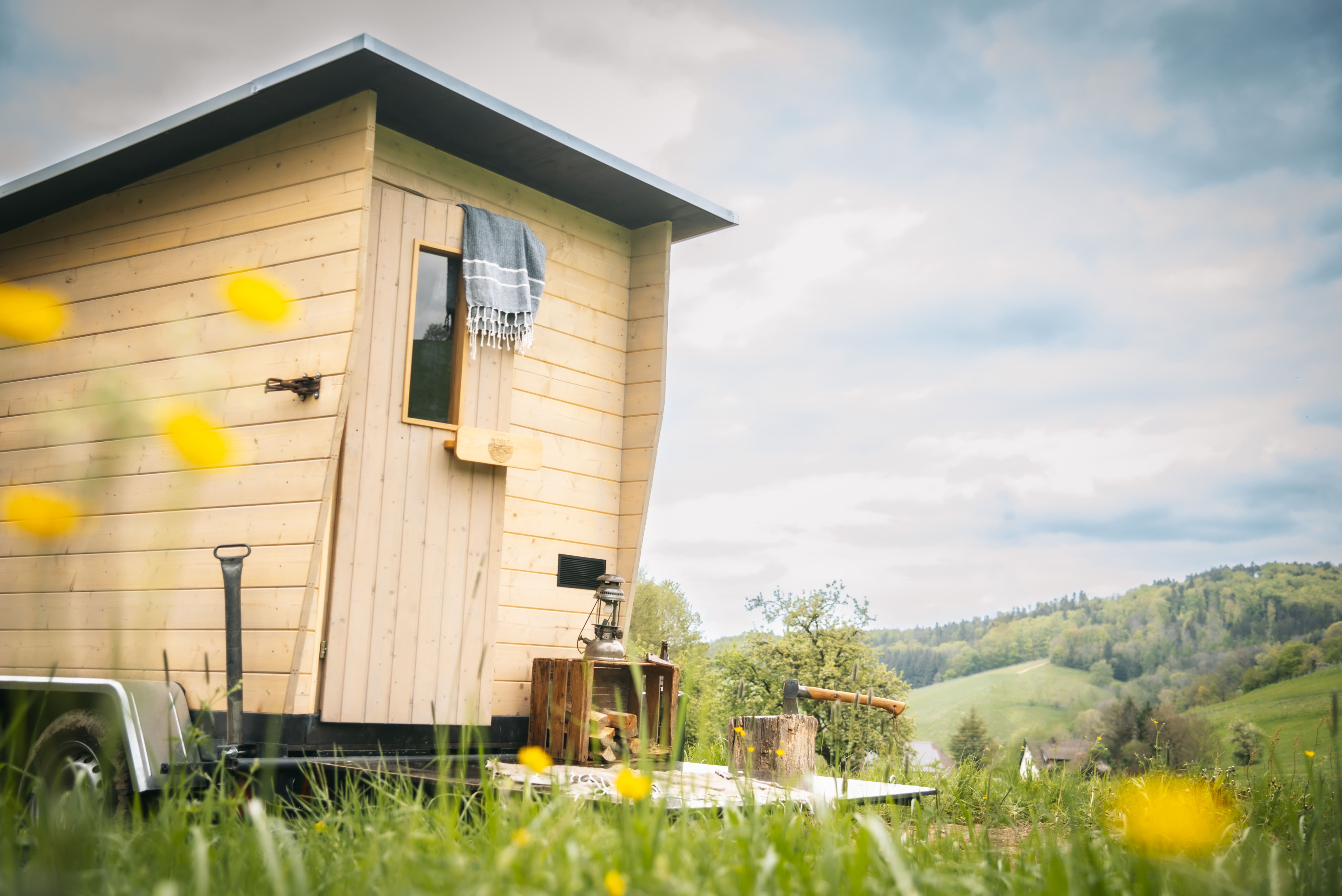 Mobile Holzsauna mit Ofen: Das Foto zeigt eine kompakte mobile Sauna, die sich als Sauna-Idee perfekt für Standorte im Schwarzwald oder in der Umgebung von Freiburg eignet.