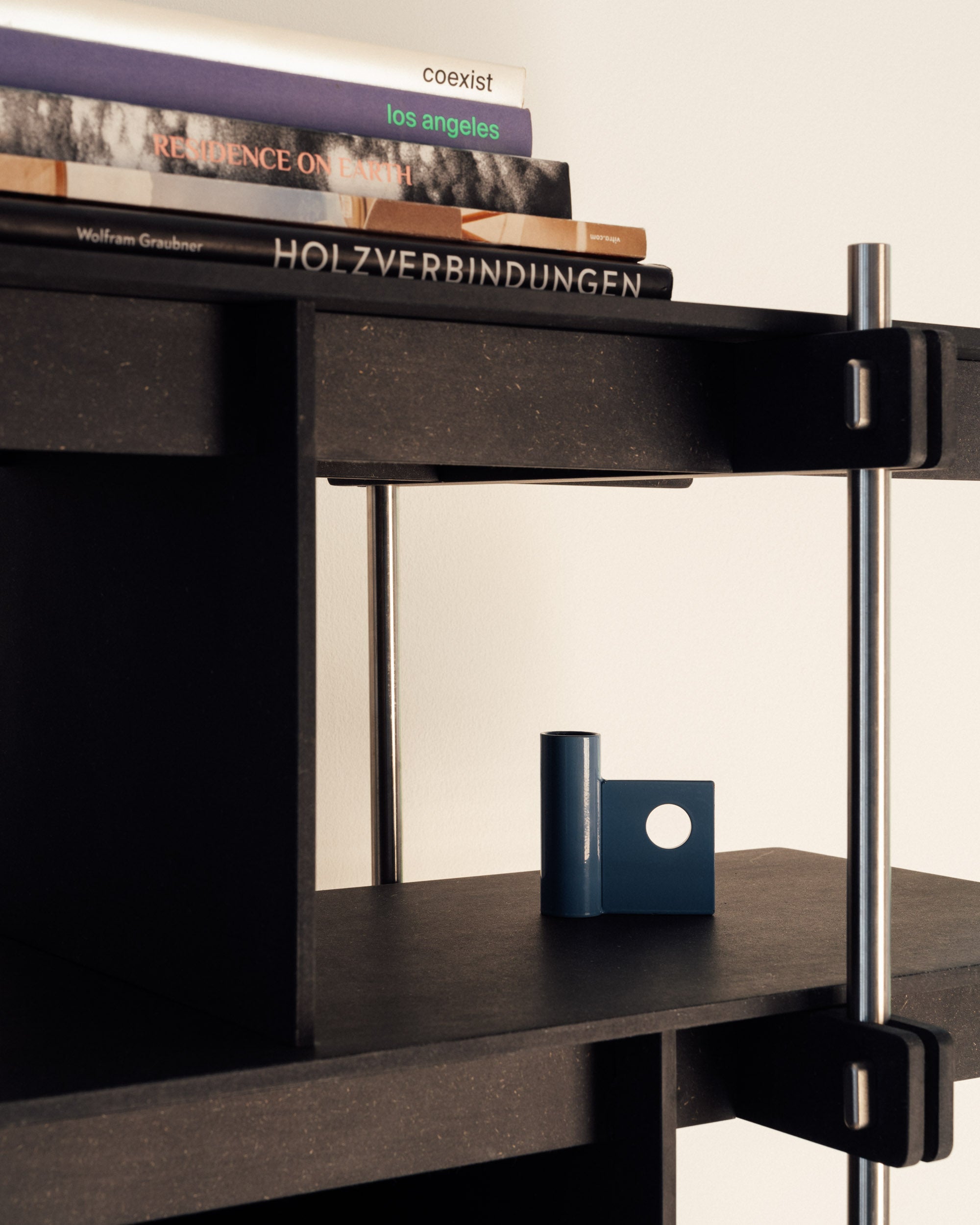 Schwarzes Design Regal aus Holz und Edelstahl mit offenem Fach und Bücherablage.