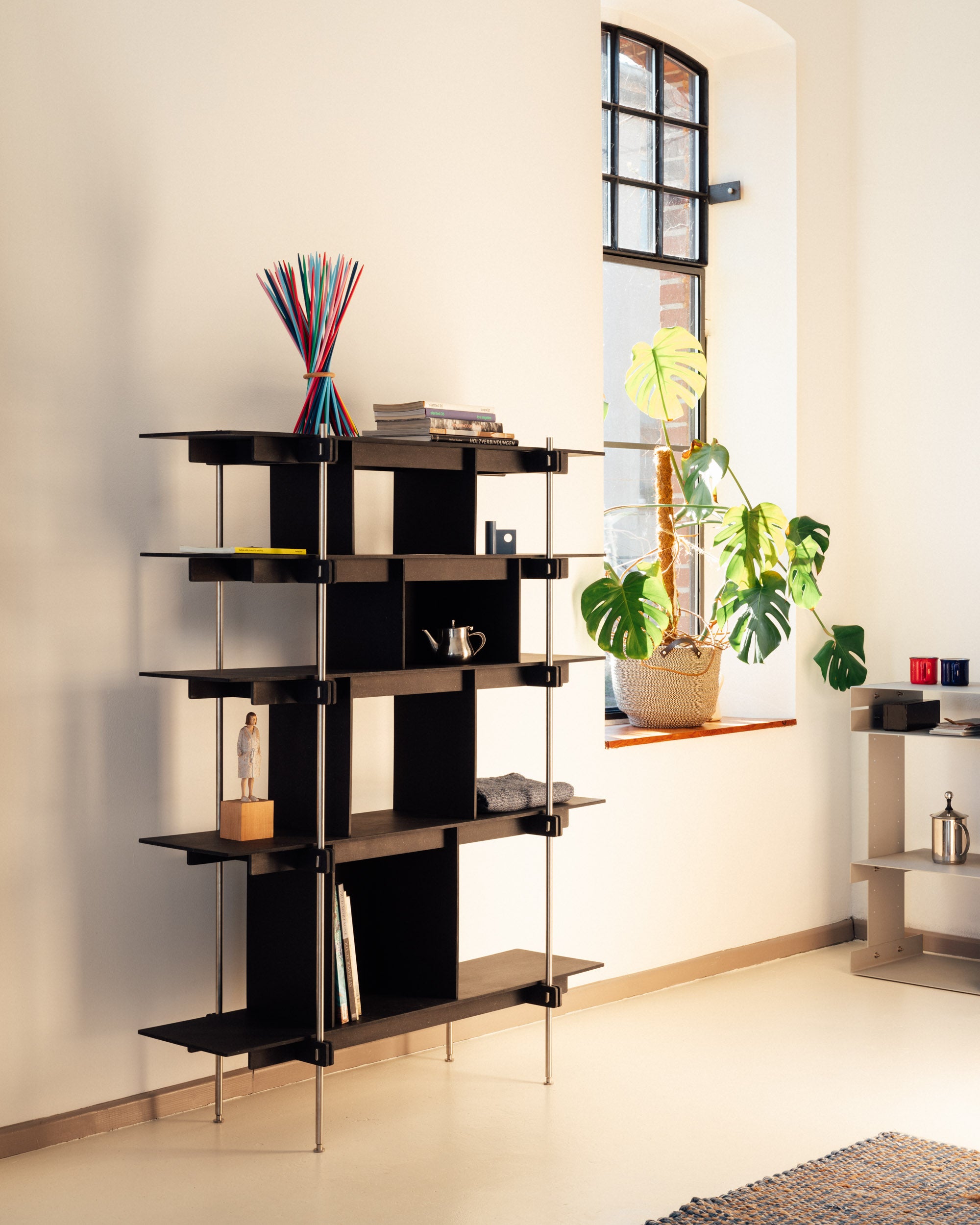 Schwarzes Design Regal aus Stahl mit mehreren offenen Fächern und klarglasböden, modernes Regalsystem Holz und offenes Regal.