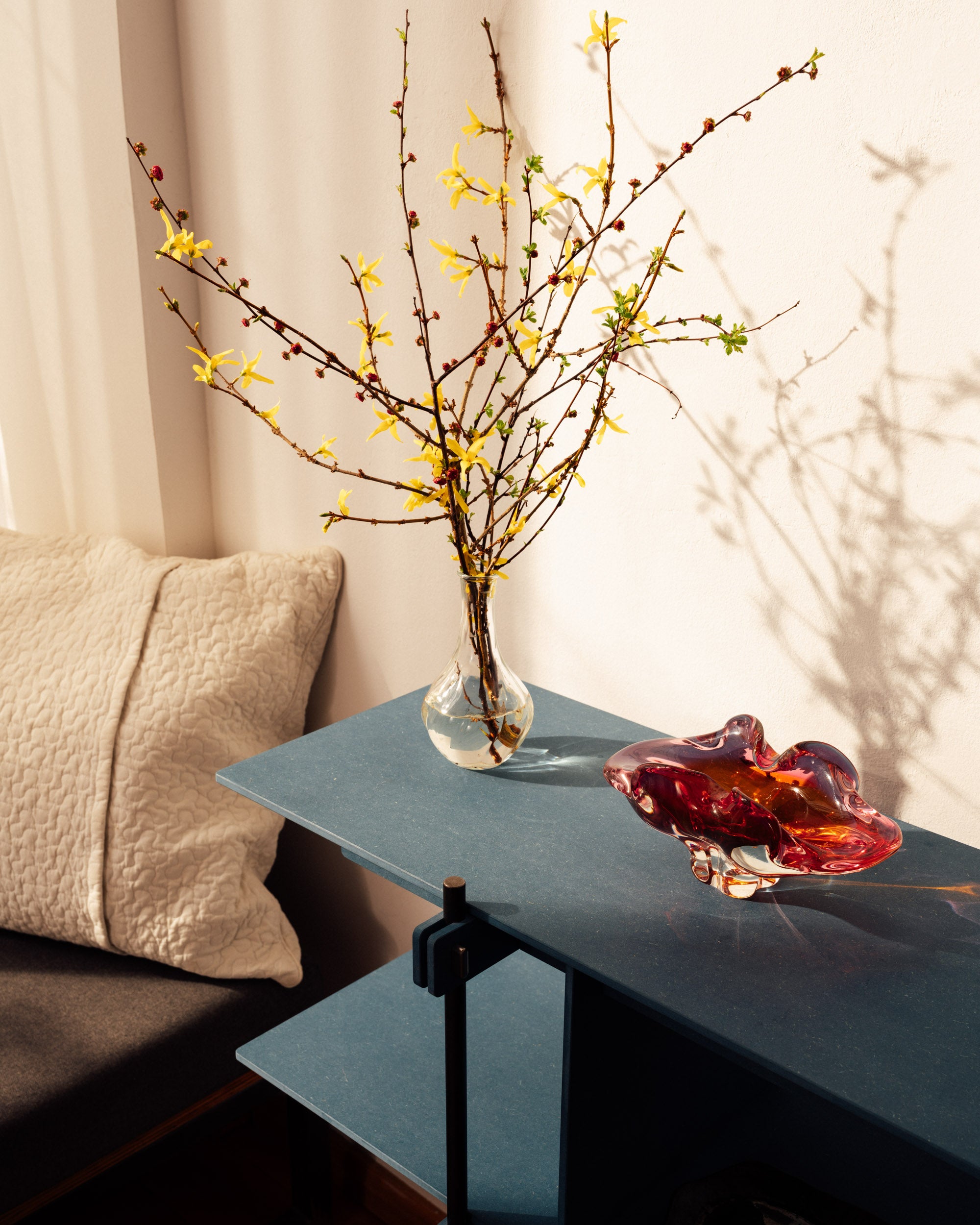 Blaues Design Regal mit Stahlrahmen, offenes Regalsystem Holz mit dekorativen Zweigen und Glasvase.