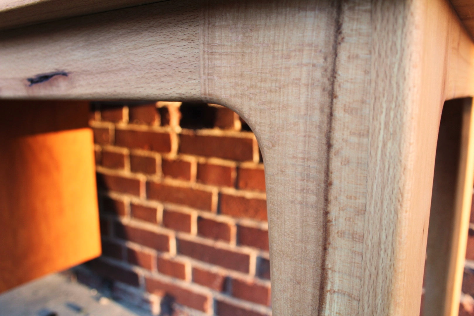 Detailaufnahme eines hellen Esstisch Holz mit geschwungenem Eckdesign und sichtbarer Maserung, Holztisch Freiburg,.