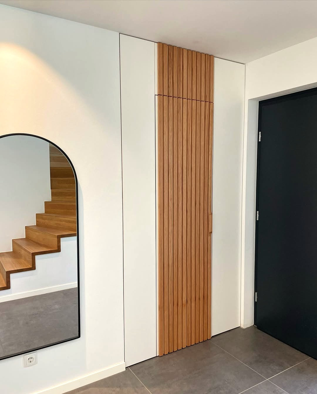 Einbauschrank unter der Treppe mit vertikalen Holzelementen, Maßanfertigung für individuellen Stauraum.