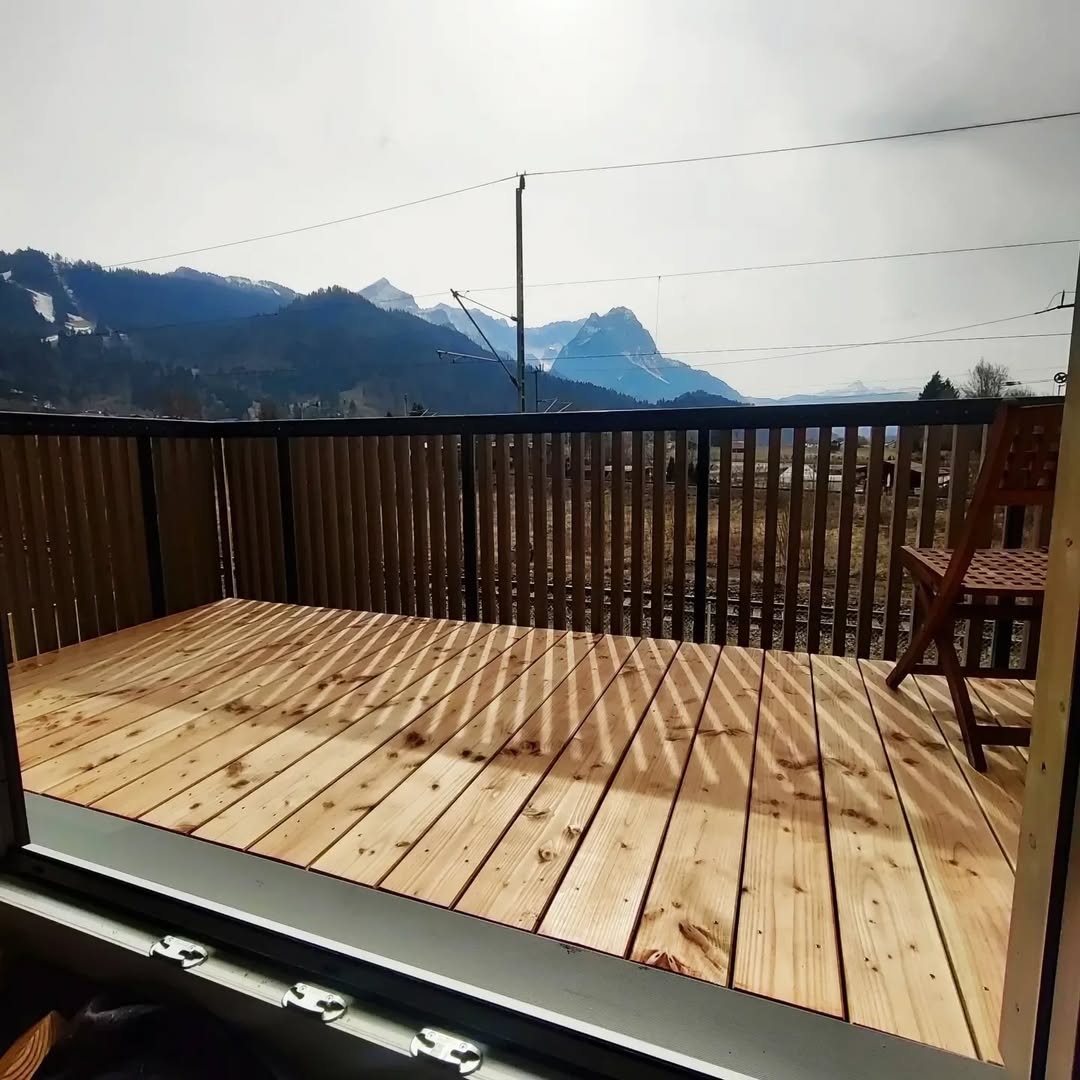 Terrasse aus Holz mit Balkongeländer und Bergblick, Balkon Holz mit klarer Balkenstruktur.