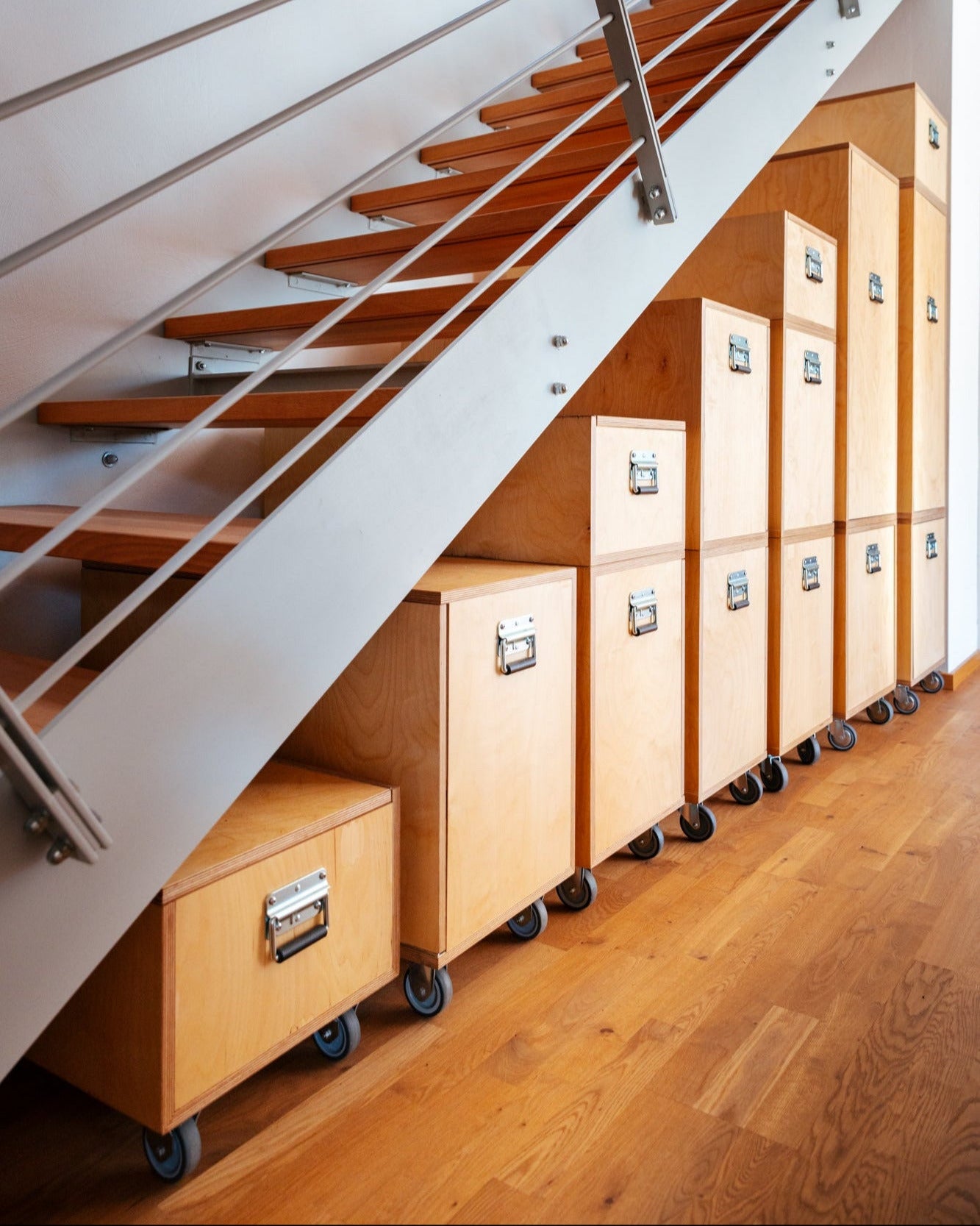 Einbauschrank unter der Treppe mit maßgefertigten, rollbaren Schränken aus Holz für individuelle Ordnung.