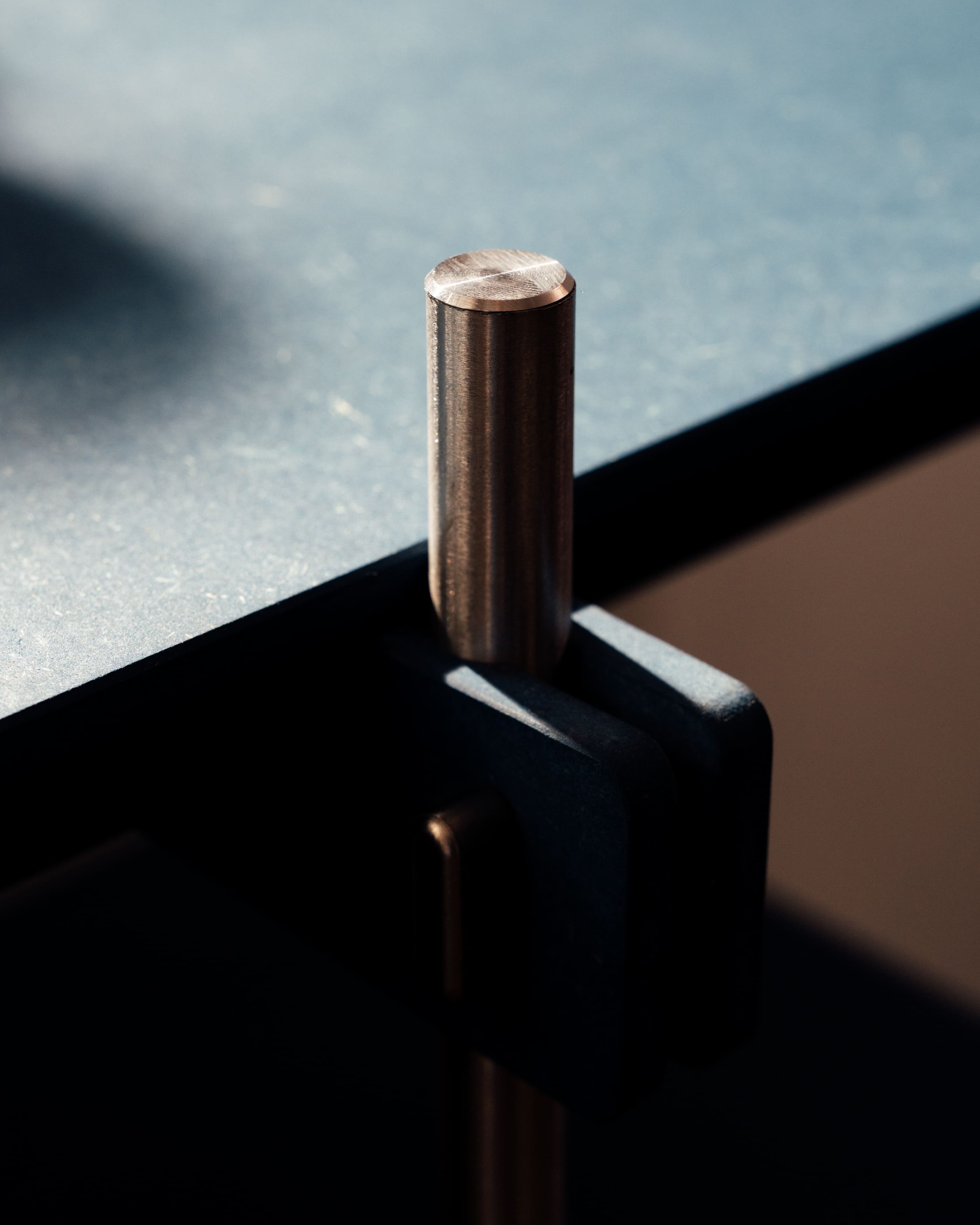 Metallischer Dübel oder Verbindungselement aus Edelstahl mit zylindrischer Form und glatter Oberfläche auf dunklem.