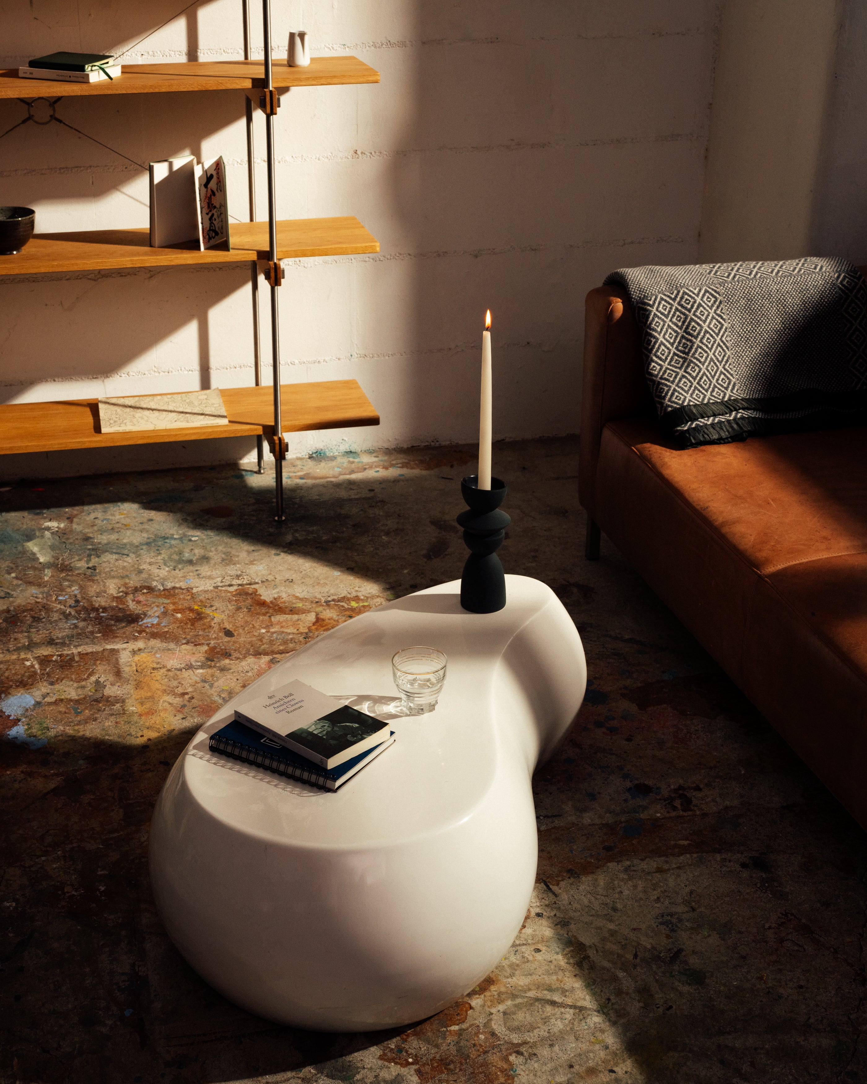 Modernes offenes Regal aus Holz mit Stahlrahmen, kombiniert mit braunem Ledersofa und weißem Design-Couchtisch.