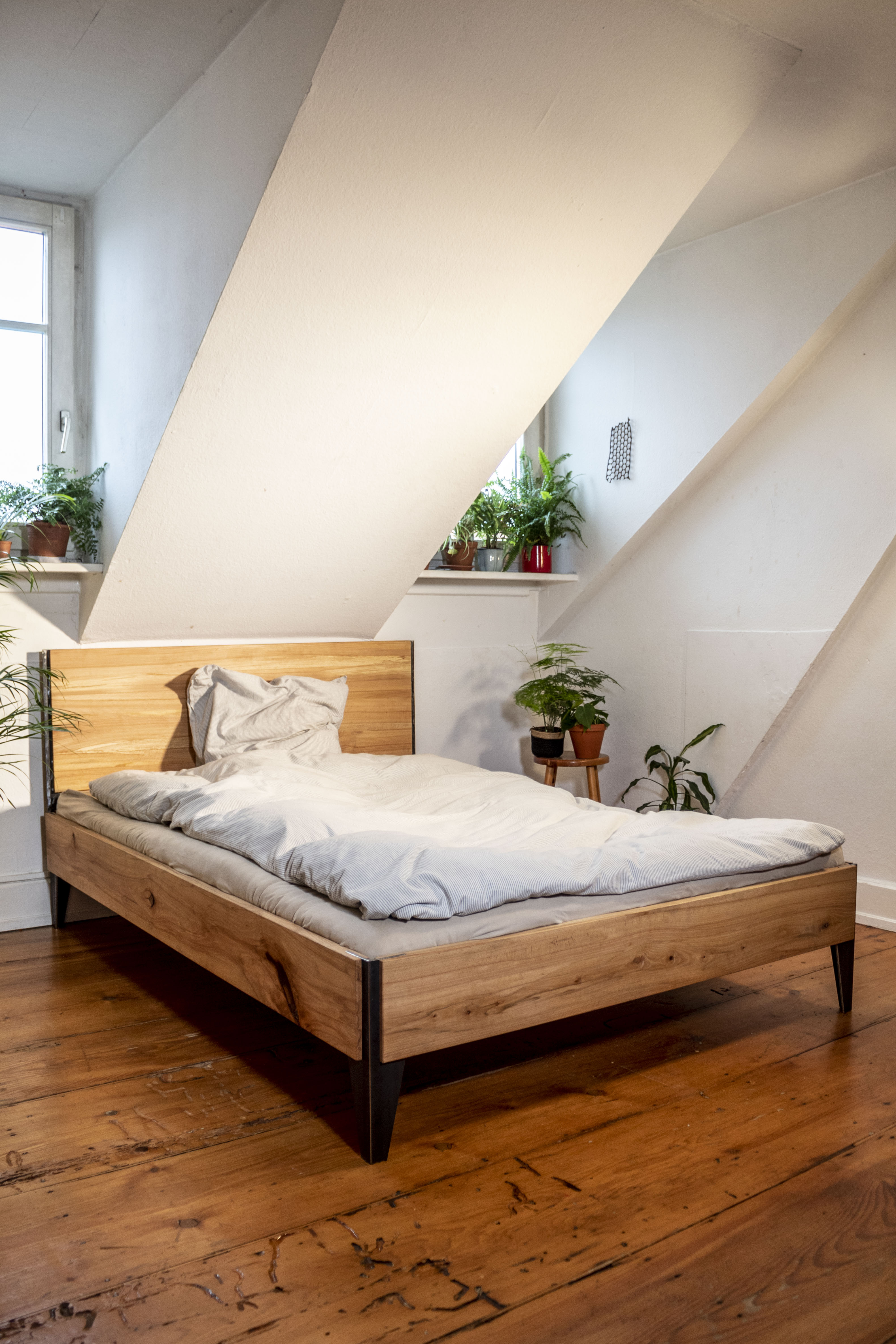 Schlafzimmer mit Bettrahmen aus Holz und Stahl, schlichtes Regalsystem Design im Hintergrund.